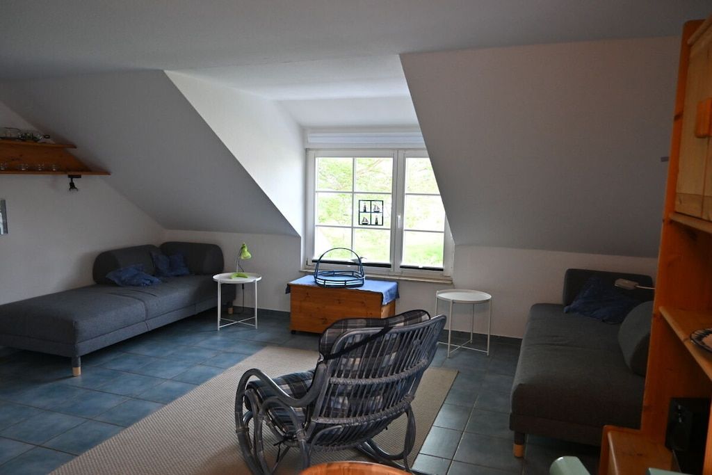 Ein Loft-Wohnzimmer mit hohen Decken, einem großen Fenster und Blick ins Freie.