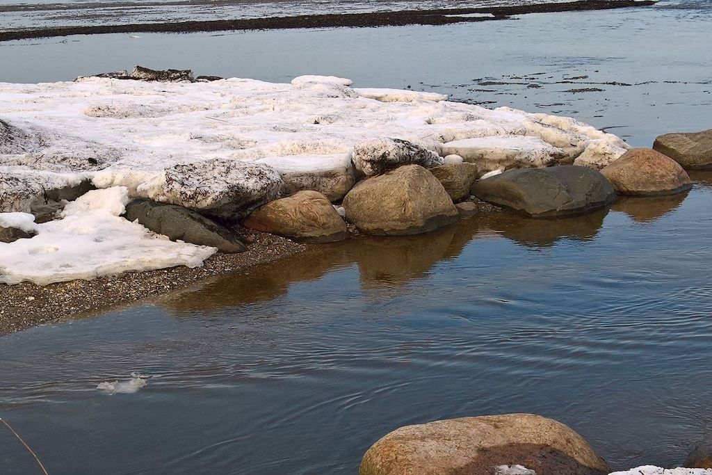 A frozen river with large rocks and ice formations.