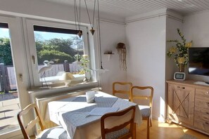 Ein Essbereich mit Tisch, Stühlen, einem Fenster mit Aussicht, einem Fernseher und einem Schrank.