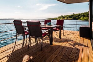 A deck with a table and chairs, overlooking a body of water.
