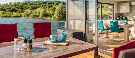 A dining area with a table, chairs, and a view of a lake.