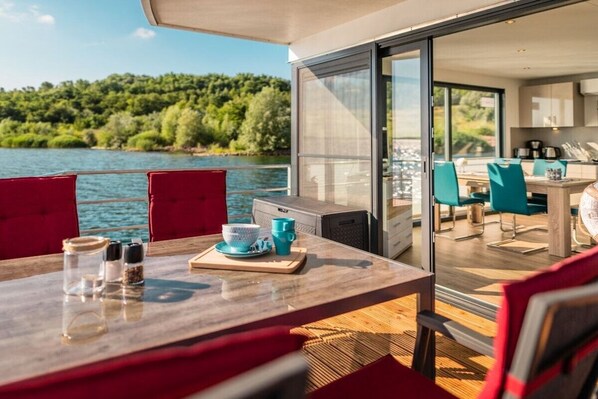 A dining area with a table, chairs, and a view of a lake.