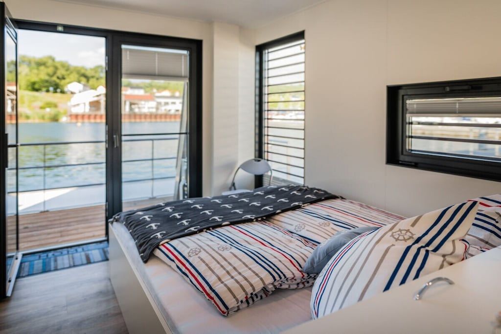 Une chambre à coucher avec un lit, une fenêtre et une vue sur une étendue d’eau.
