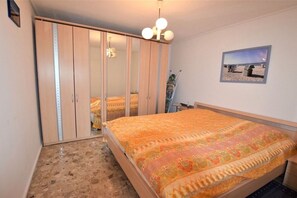 Une chambre à coucher avec un lit, une armoire, un miroir et un tableau accroché au mur.