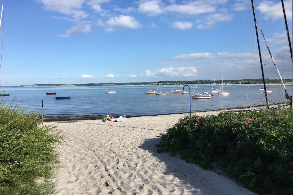 Una playa arenosa con barcos en el agua y un cielo despejado.