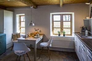 A kitchen with a wooden table, chairs, a window, and a radiator. - Holiday home in Schlei with 2 bedrooms (Klappholz)