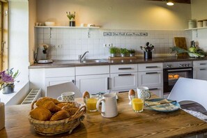 Eine Küche mit weißen Schränken, einer Kaffeemaschine, einem Spülbecken und einer Frühstücksvorrichtung mit Brot, Eiern und Saft.