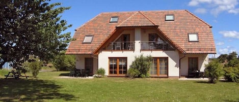 A two-story house with a sloped roof, large windows, and a balcony.
