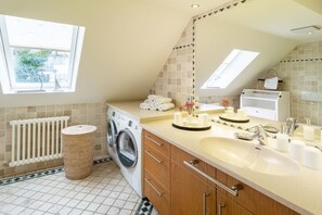 Een moderne badkamer met een ingebouwde wasmachine, een grote spiegel en een raam voor natuurlijk licht.