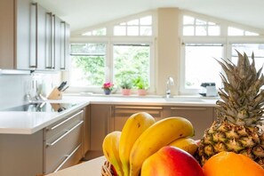 Een keuken met een fruitschaal met bananen, ananas en een sinaasappel.