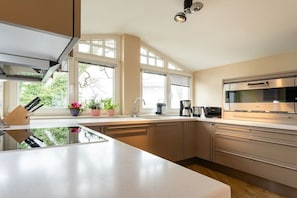 A modern kitchen with a central island, stainless steel appliances, and large windows. - Penthouse Villa Gudrun with private sauna (Ostseebad Binz)