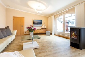 A modern living room with a sofa, a glass coffee table, a fireplace, and a large window with a view. - Penthouse Villa Gudrun with private sauna (Ostseebad Binz)