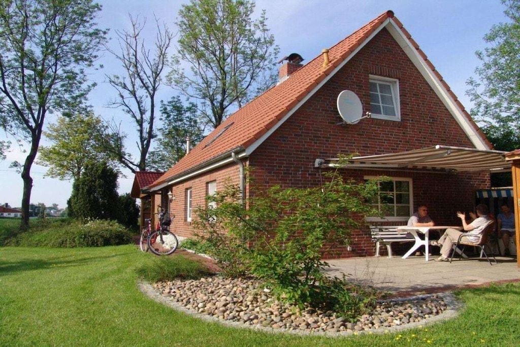 A brick house with a sloped roof, a satellite dish, and a patio with a table and chairs.