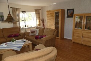 Ein Wohnzimmer mit einer Couch, Sesseln, einem Couchtisch und einem Schrank.