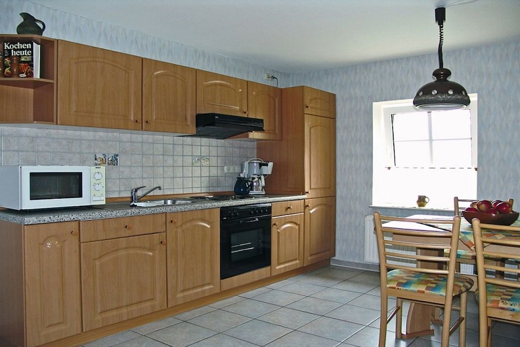 A kitchen with wooden cabinets, a microwave, a stove, and a window with a view.