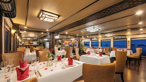 Een eetgedeelte met tafels voor twee personen, met witte tafellinnen, rode servetten en glazen.