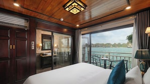 Een hotelkamer met een groot bed, een badkamer met een glazen deur en uitzicht op zee.