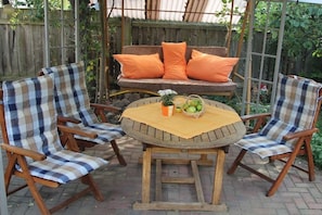 A round wooden table with a checkered tablecloth, surrounded by four wooden chairs with checkered cushions. - Holiday apartment with 1 bedroom (Lübbenau)