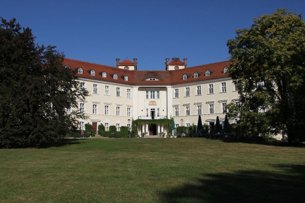 A large, symmetrical building with a central entrance, surrounded by a well-maintained lawn.