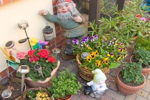A garden with potted plants and a statue of a gnome. - Holiday apartment with 1 bedroom (Lübbenau)