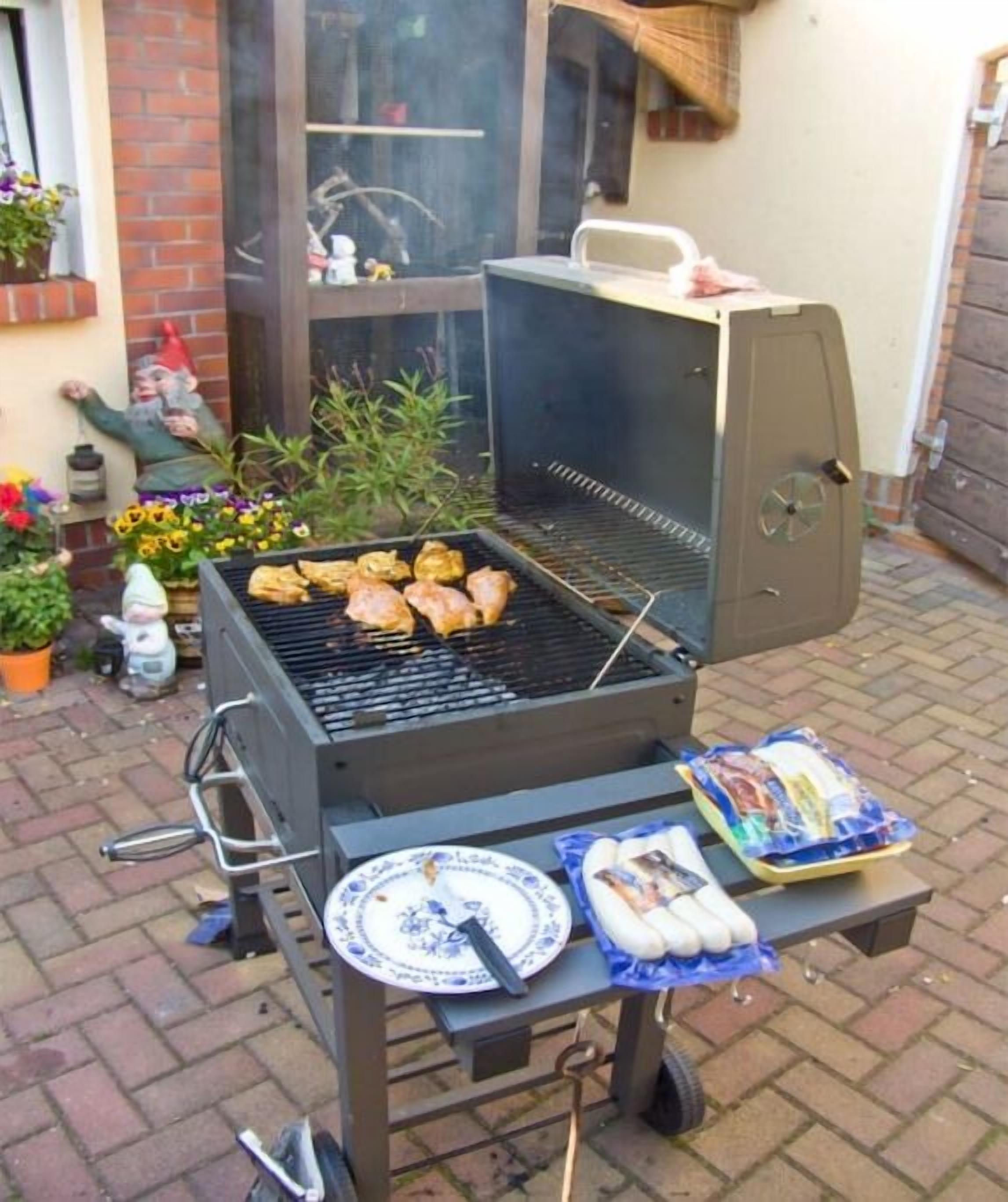 Un barbecue avec de la nourriture, une table avec des assiettes et une terrasse en briques.