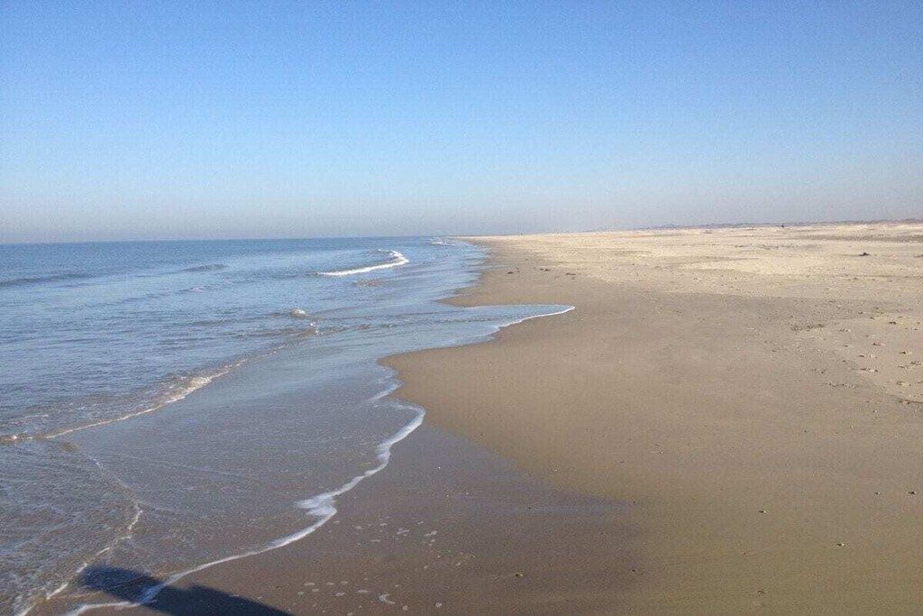 Una playa con cielo despejado y mar tranquilo.