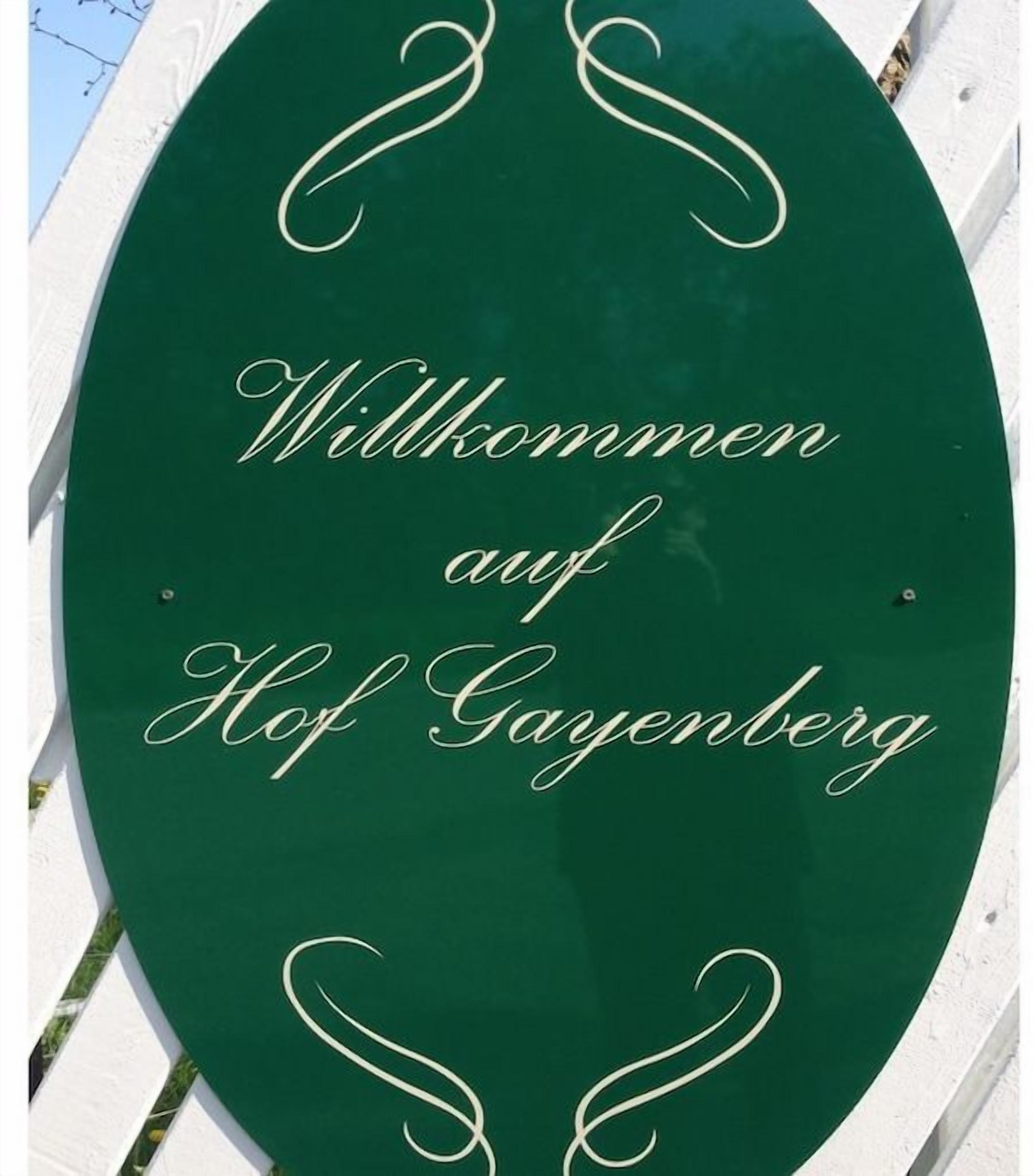 A green sign with white cursive text welcoming guests to Hof Gayenberg.