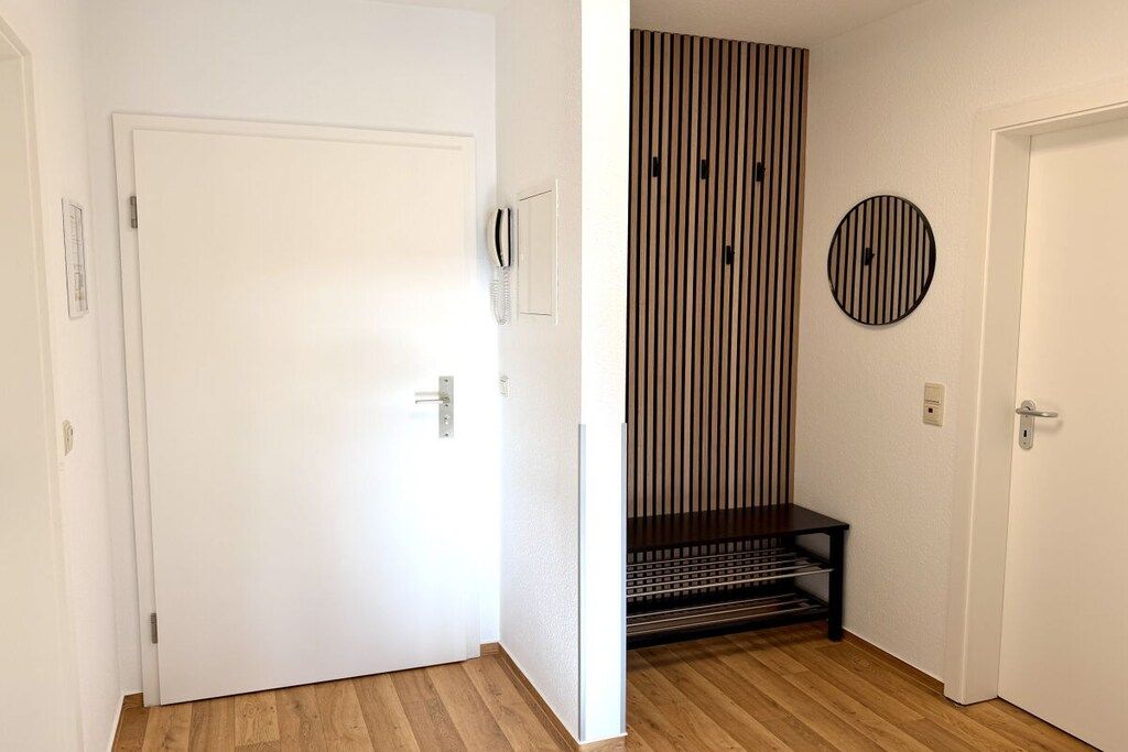 A hallway with a white door, a wall-mounted telephone, and a striped vertical panel.