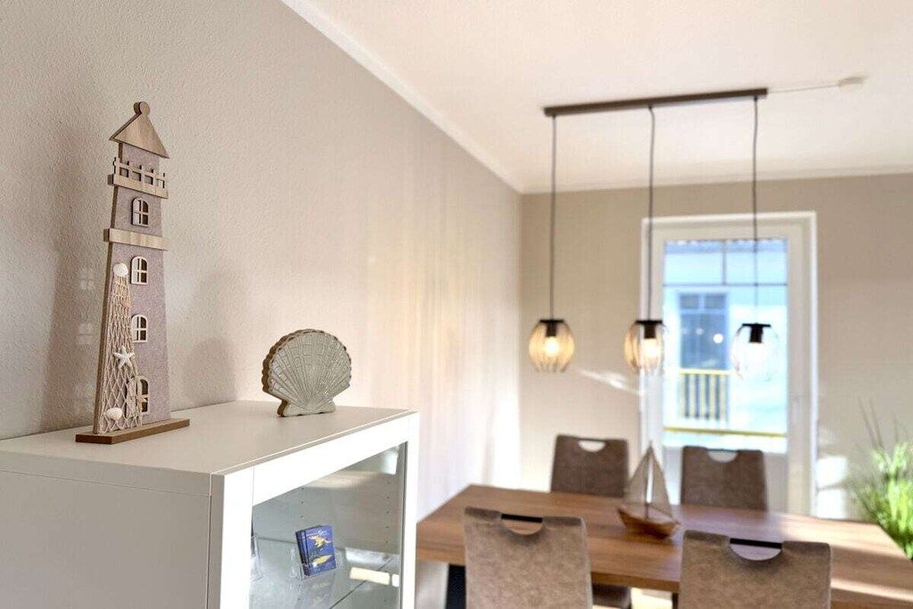 A dining area with a tall, narrow tower-like structure on a white cabinet, a glass display case, and a wooden dining table with chairs.