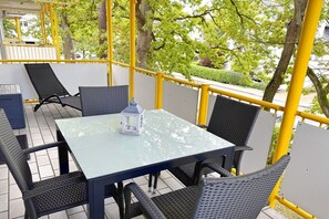 An outdoor seating area with a table and chairs, a lantern, and yellow railings. - Holiday apartment KÜSTENNEST Baabe (Baabe)