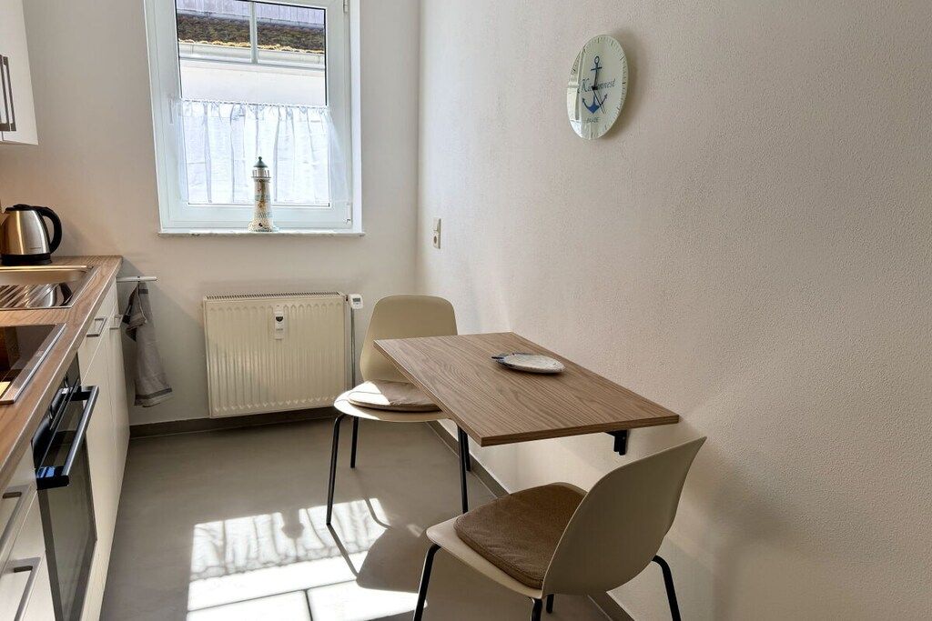 A kitchen with a window, a radiator, a kettle, and a table with chairs.