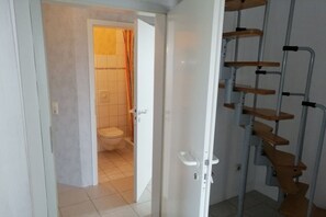 A bathroom with a toilet, a shower area, and a white door. - Holiday apartment in Süsel with swimming pool (Süsel)