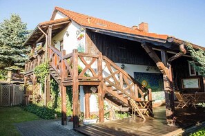 A wooden house with a staircase leading to a deck. - Stein - Apartment Storchenblick (Byhleguhre)