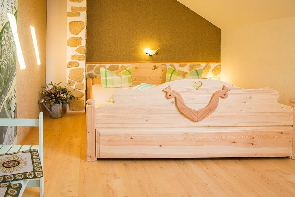 Ein Schlafzimmer mit einem hölzernen Bett, einer Wandverkleidung aus Stein und einer Wandleuchte.
