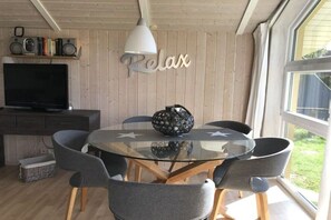 A dining area with a glass table, grey chairs, a decorative bowl, and a 'Relax' sign on the wall. - Holiday home in the Baltic Sea with 2 bedrooms (Boiensdorf Stove)