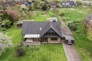 A residential property with a sloped roof, a covered porch, and a driveway leading to a parked car. - Bergner's Country House (Hollern-Twielenfleth)