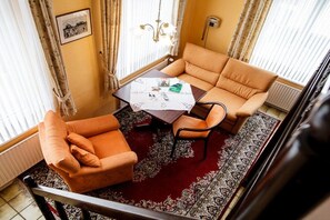 Ein Wohnzimmer mit einer Couch, Sesseln, einem Couchtisch und einem gemusterten Teppich.