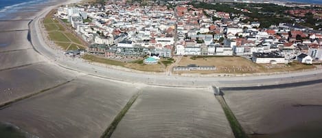 An aerial view of a coastal town with a beach, residential buildings, and a large open area.