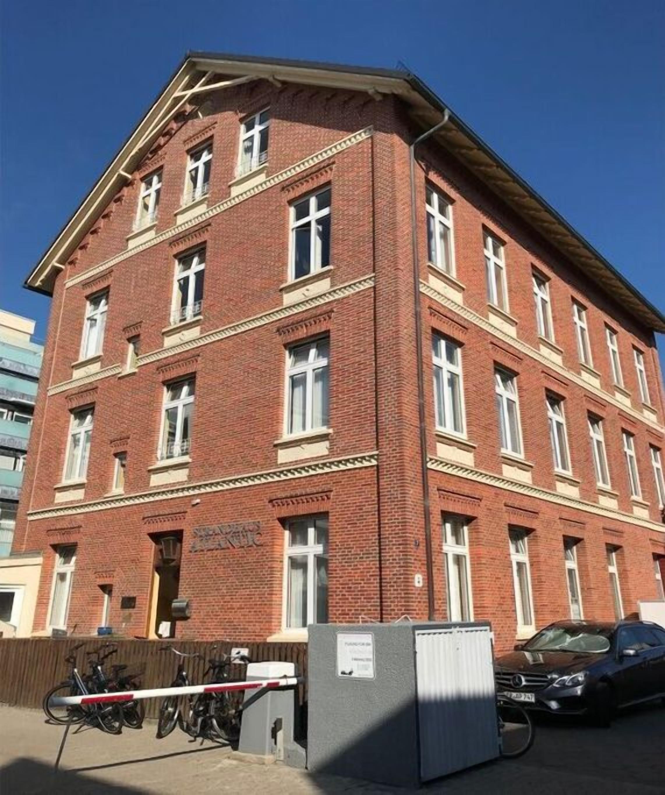 A red brick building with multiple windows and a gated entrance.