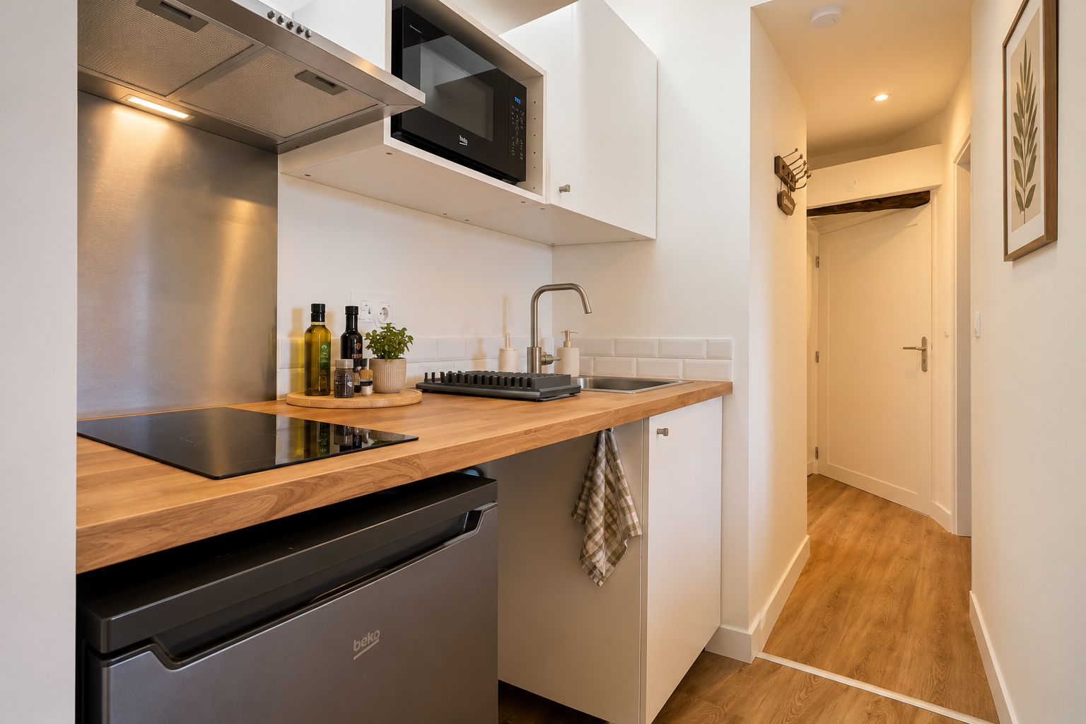 Una cocina compacta con microondas integrado, fregadero y lavavajillas.