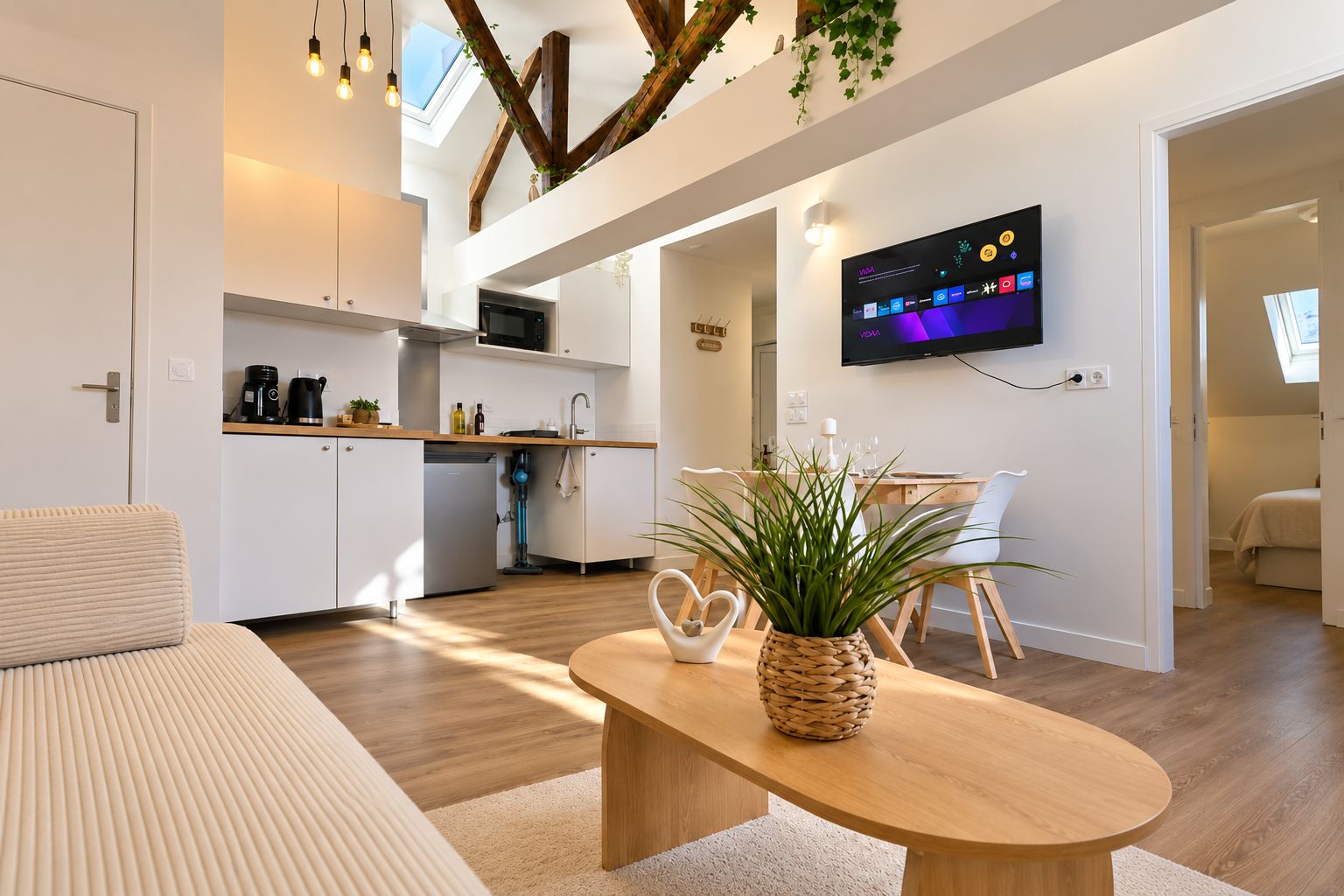Un espace de vie moderne comprenant une cuisine, un coin repas et un téléviseur fixé au mur.