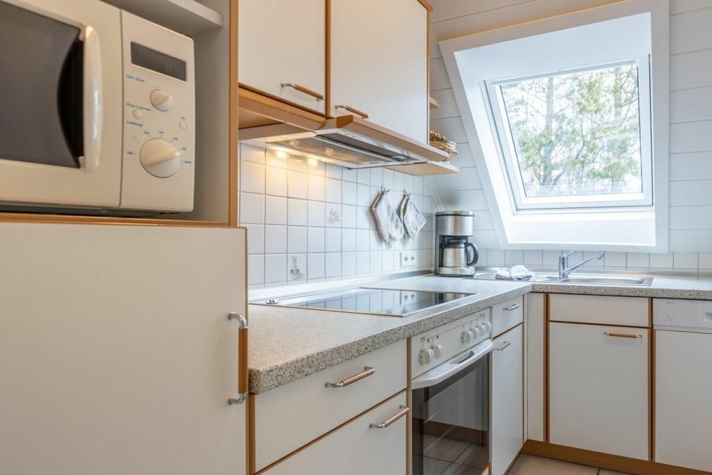 Une cuisine moderne équipée d’un four à micro-ondes, d’une cuisinière, d’un four et d’une fenêtre située au-dessus de l’évier.