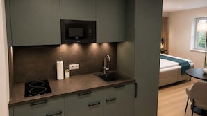 Una cucina compatta con forno a microonde integrato, un lavandino e un piano di lavoro con dispenser per sapone.
