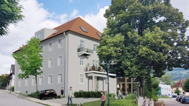 Un edificio residenziale a più piani con tetto piatto, balconi e un prato ben curato.