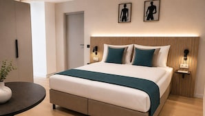Una camera d'albergo moderna con un letto, comodini, un tavolino rotondo e una sedia.