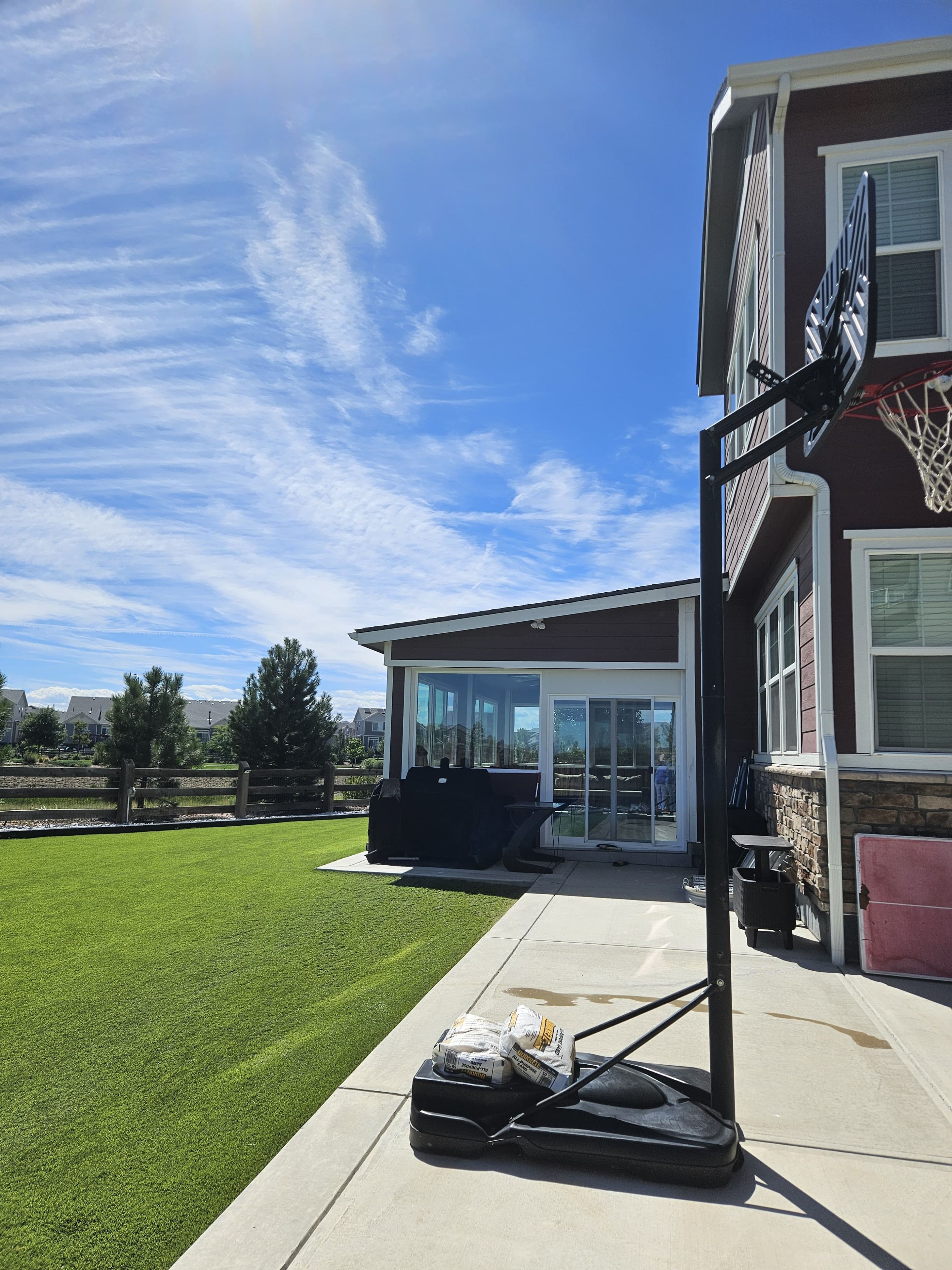 A residential property with a basketball hoop, a patio with outdoor furniture, and a well-maintained lawn.