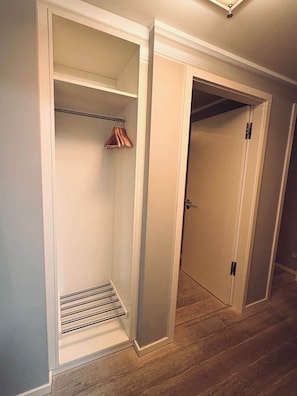 A walk-in closet with a metal rod and wooden hangers, a door with a handle, and a wooden floor. - Prora Select Vacation Rental in Prora for up to 5 people (Binz)