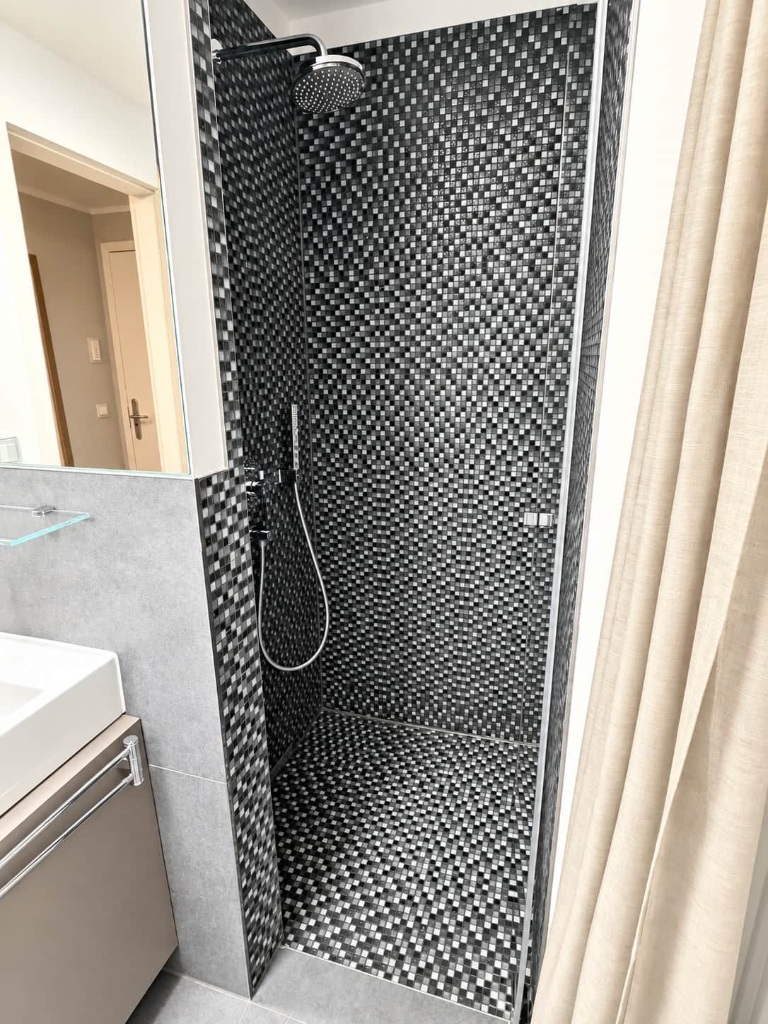 Une douche dont le carrelage est composé de motifs à carreaux noirs et blancs.