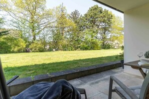 A patio with a view of a grassy yard and trees. - Villa Anna II, Apartment 71 (St. Peter - Ording)