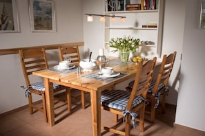 Ein Holztisch mit Stühlen, eine Vase mit Blumen und ein Bücherregal.
